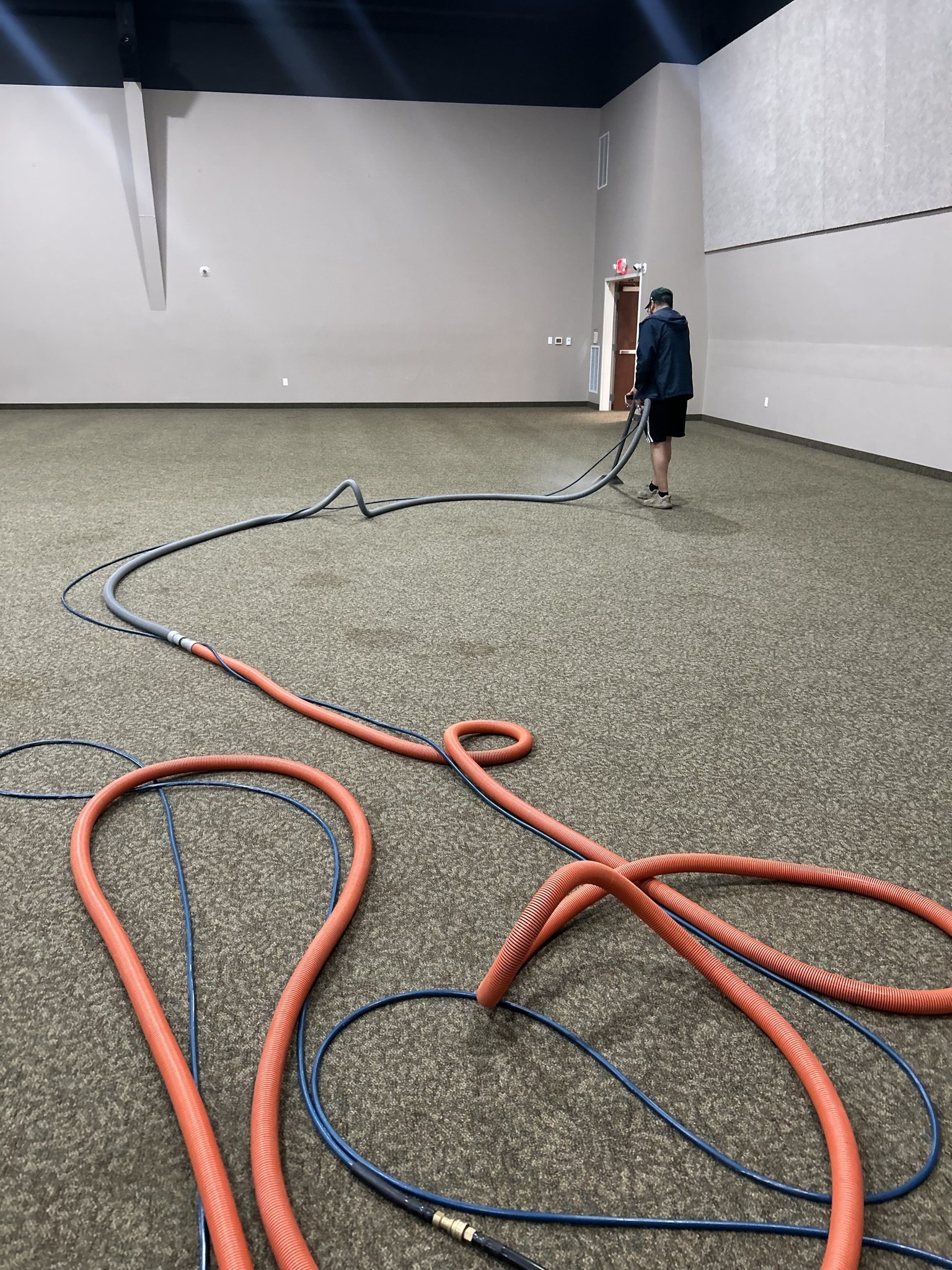 Large commercial facility carpet cleaning in progress — open room, hoses, and extraction equipment