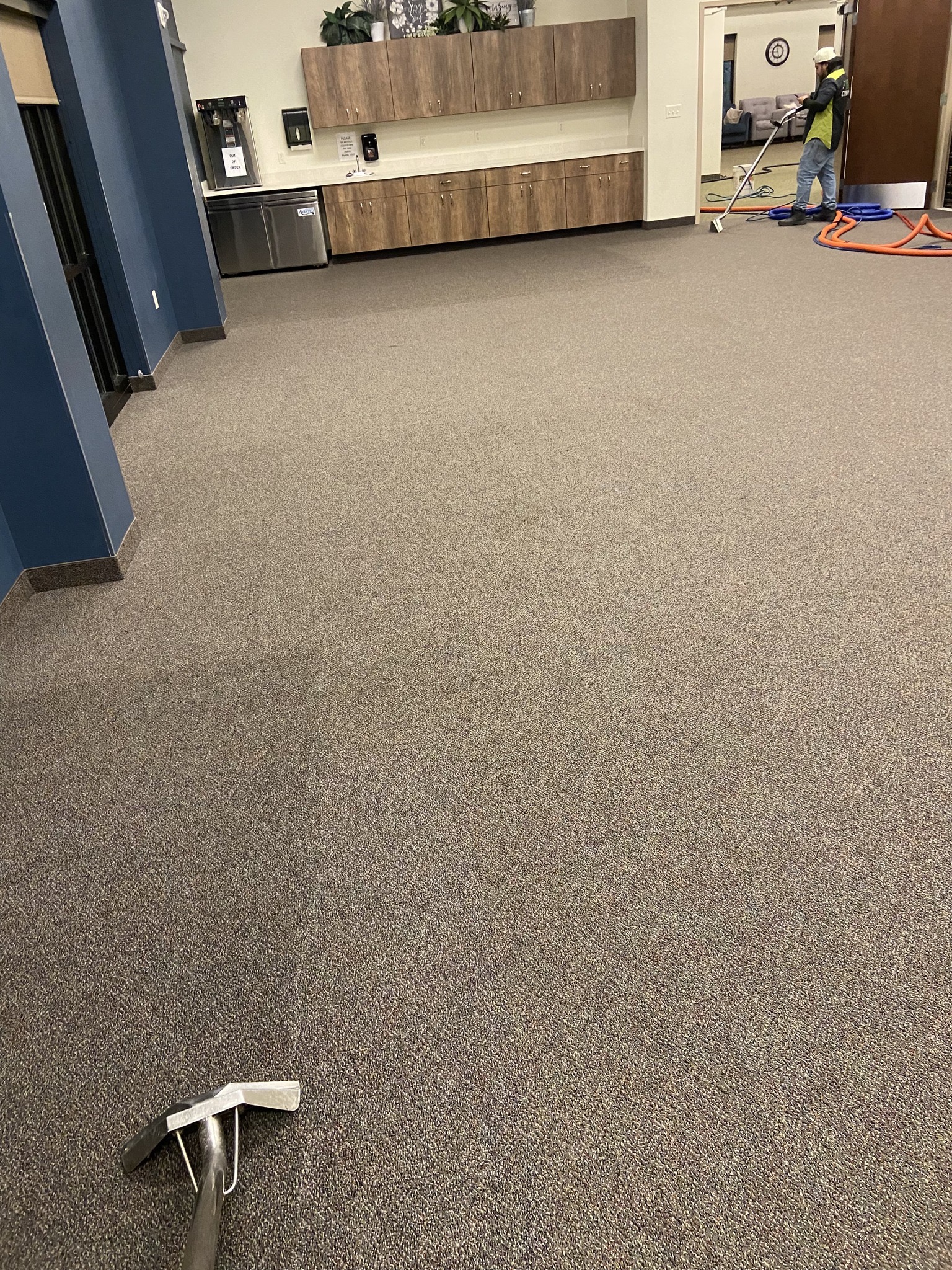 Commercial facility carpet cleaning — technician with wand, hose, and extraction equipment